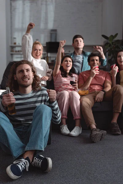 Excited friends showing winner gesture while watching championship at home — Stock Photo