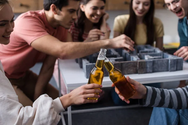 KYIV, UKRAINE - 27 JANVIER 2020 : mise au point sélective de la fille et le gars cliquetis bouteilles de bière près des amis jouer jeu de labyrinthe — Photo de stock