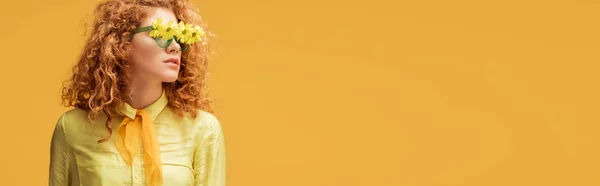 Plan panoramique de femme rousse élégante en lunettes de soleil avec des fleurs isolées sur jaune — Photo de stock