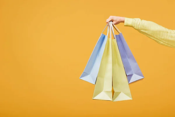Cropped view of young woman holding shopping bags isolated on yellow — Stock Photo