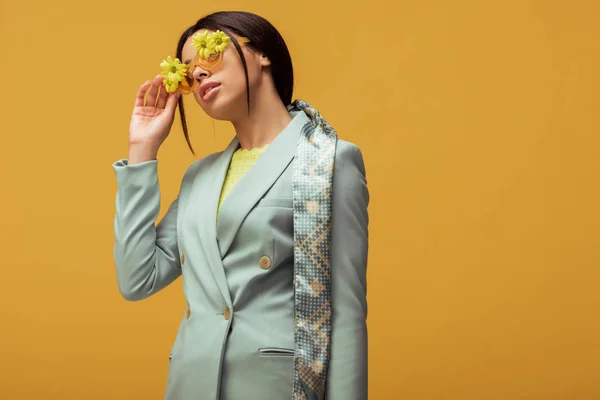 Trendige afrikanisch-amerikanische Mädchen in Anzug und Schal berühren Sonnenbrille mit Blumen isoliert auf gelb — Stockfoto