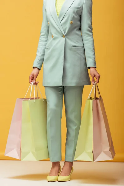 Afro-américaine fille en costume tenant des sacs à provisions sur jaune — Photo de stock