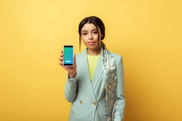 KYIV, UCRAINA - 4 FEBBRAIO 2020: bellissima ragazza afroamericana con smartphone in mano con app twitter su giallo — Foto stock