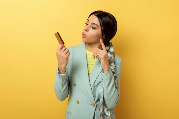 Pensive african american girl looking at credit card and pointing with finger on yellow — Stock Photo