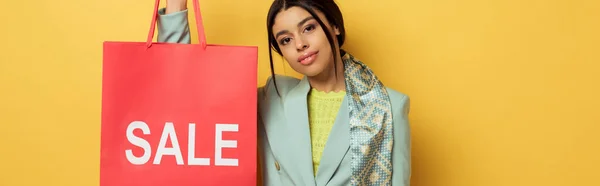 Colpo panoramico di attraente ragazza afro-americana in possesso di shopping bag con iscrizione in vendita su giallo — Foto stock