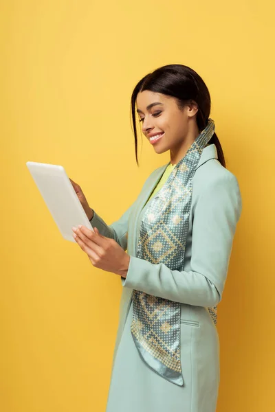 Mulher americana africana feliz usando tablet digital isolado em amarelo — Fotografia de Stock