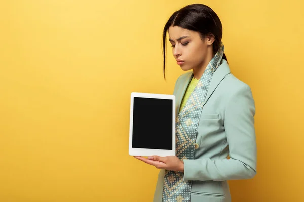 Mulher afro-americana descontente segurando tablet digital com tela em branco no amarelo — Fotografia de Stock