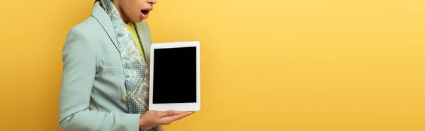 Plan panoramique de femme afro-américaine choquée tenant tablette numérique avec écran blanc isolé sur jaune — Photo de stock