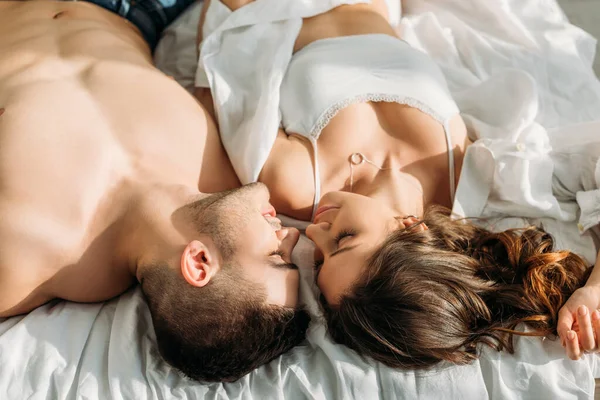 Над головой вид сексуальных мужчин и женщин, лежащих лицом к лицу с закрытыми глазами — стоковое фото
