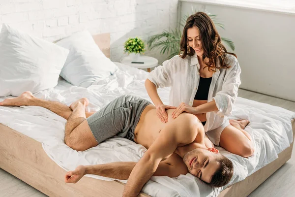 Sexy chica en blanco camisa haciendo espalda erótico masaje a sexy novio - foto de stock