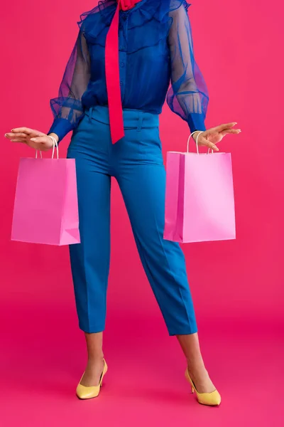 Vista cortada de menina segurando sacos de compras, em rosa — Fotografia de Stock