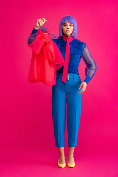 Pop art girl in purple wig holding hanger with red blouse, on pink — Stock Photo