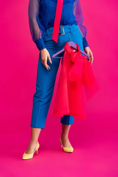 Cropped view of girl holding hanger with red blouse, on pink — Stock Photo