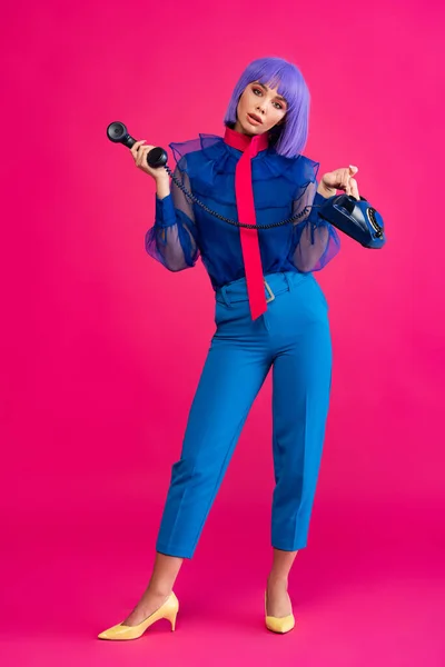 Fashionable girl in purple wig holding retro phone, on pink — Stock Photo