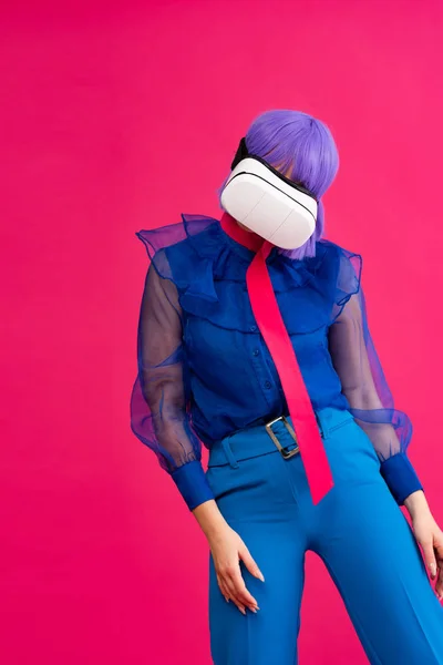 Pop art girl en blusa azul y peluca púrpura usando auriculares de realidad virtual, aislados en rosa - foto de stock