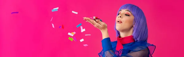 Panoramic shot of stylish beautiful pop art woman in purple wig blowing confetti, isolated on pink — Stock Photo