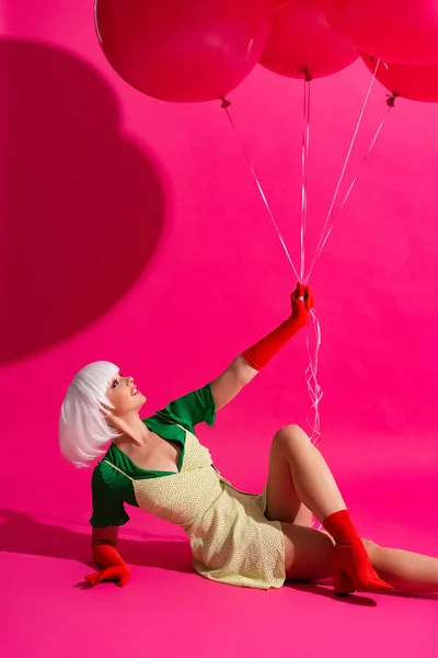 Beautiful fashionable girl in white wig holding balloons on pink — Stock Photo