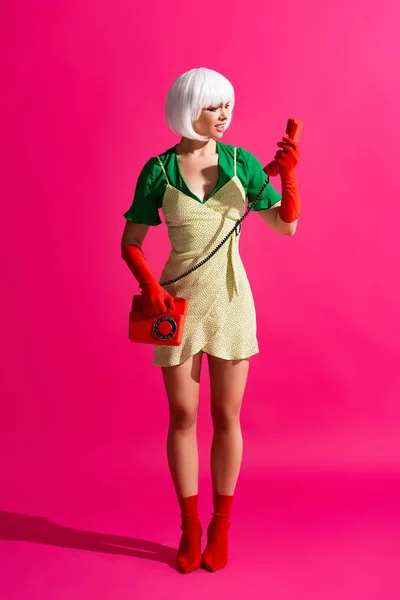 Shocked pop art girl in white wig talking on retro telephone, on pink — Stock Photo