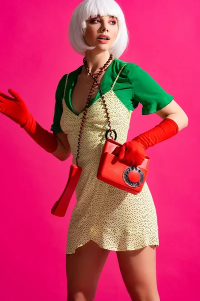 Surprised pop art girl in white wig with vintage phone, isolated on pink — Stock Photo