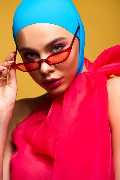 Sexy fashionable girl in trendy scarf and red sunglasses, isolated on yellow — Stock Photo