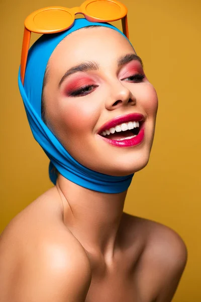 Moda sorridente ragazza in sciarpa e occhiali da sole alla moda, isolato su giallo — Foto stock