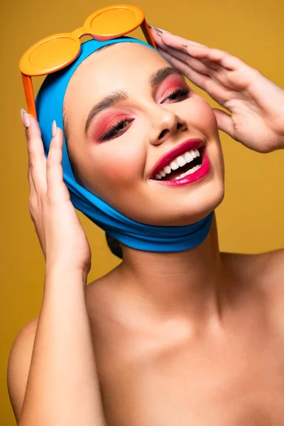 Hermosa mujer de moda riendo en bufanda y gafas de sol de moda, aislado en amarillo - foto de stock