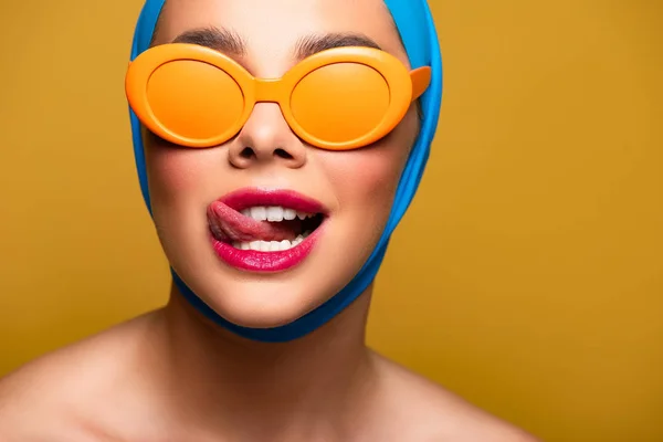 Счастливая девушка в шарфе и модных солнцезащитных очках, похожих на губы, изолированная на желтом — стоковое фото