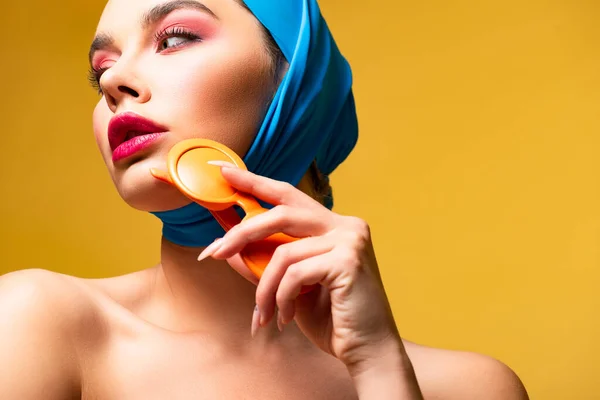 Attrayant coûteux femme nue dans l'écharpe tenant des lunettes de soleil, isolé sur jaune — Photo de stock