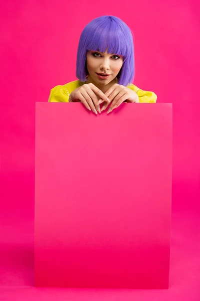 Cheerful pop art girl in purple wig holding blank placard, on pink — Stock Photo