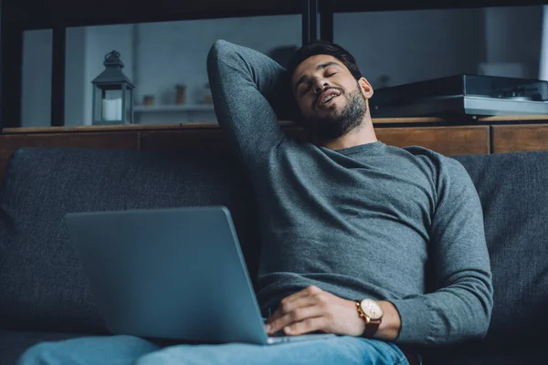 Handsome man masturbating while watching pornography on laptop on couch — Stock Photo