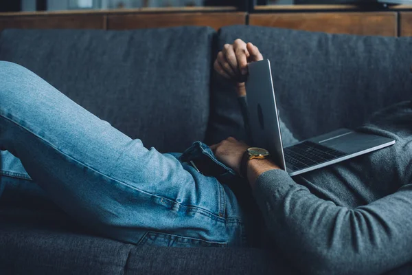 Cropped view of man masturbating while watching pornography on laptop on couch in living room — Stock Photo