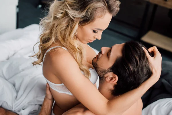 Leidenschaftliche Frau berührt Haare eines muskulösen Mannes auf dem Bett — Stockfoto
