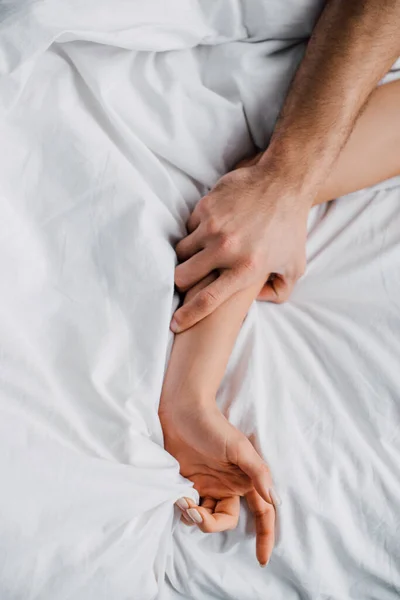 Top view of man holding hand of girlfriend on bed — Stock Photo