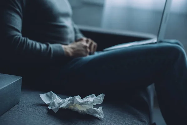 Selective focus of crumpled napkin near man masturbating while watching pornography on laptop on couch — Stock Photo