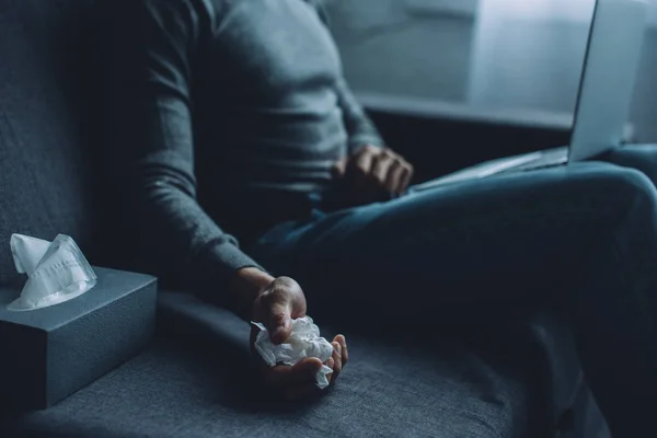 Вибірковий фокус людини, що тримає збиту серветку під час перегляду порнографії на ноутбуці на дивані — стокове фото