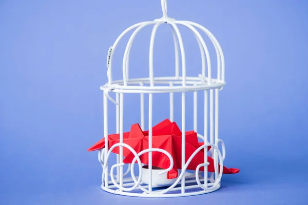 Origami birds in metallic cage on blue — Stock Photo