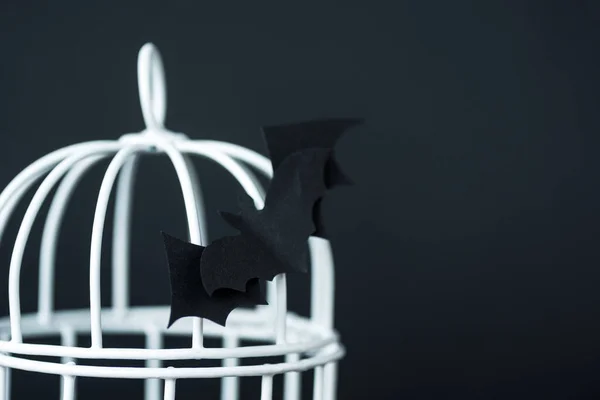 Selektiver Fokus der Origami-Fledermaus in der Nähe von metallischen Käfig isoliert auf schwarz — Stockfoto