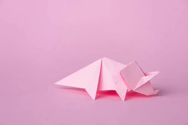 Small origami rhinoceros on pink with copy space — Stock Photo