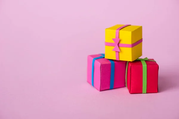 Petits cadeaux en papier coloré sur rose avec espace de copie — Photo de stock