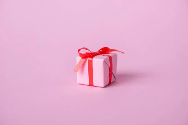 Small paper present with ribbon and bow on pink — Stock Photo