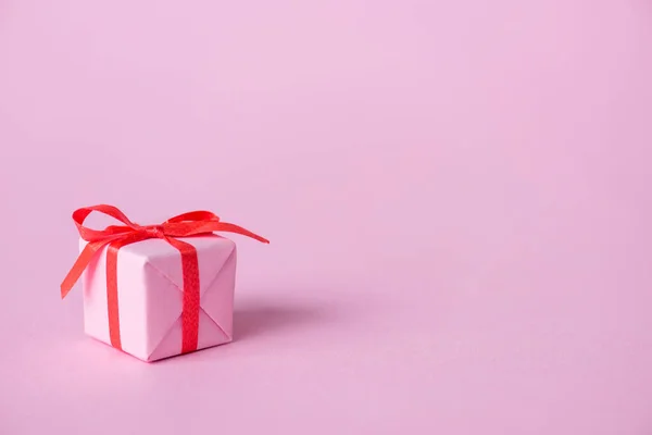 Небольшой бумажный подарок с лентой и лук на розовый — стоковое фото