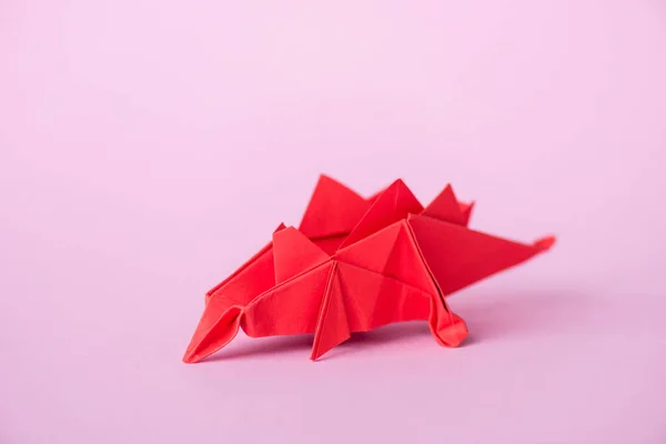 Dinosaurio origami rojo en rosa con espacio para copiar - foto de stock