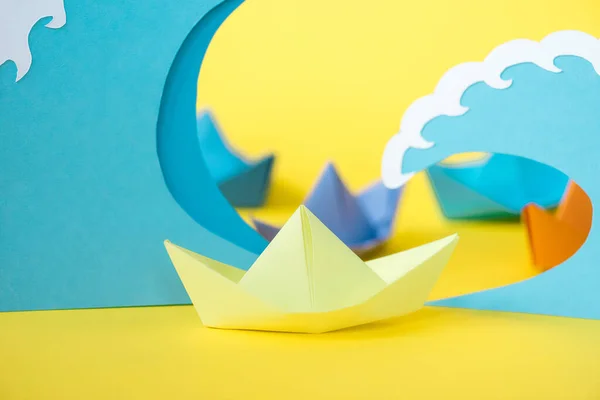 Selective focus of paper ship near waves on yellow — Stock Photo