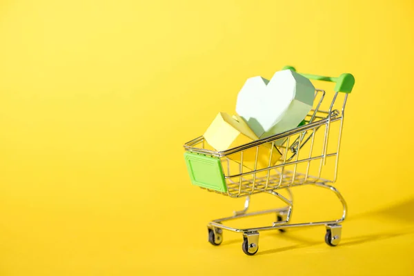 Origami hearts in toy shopping cart on yellow — Stock Photo