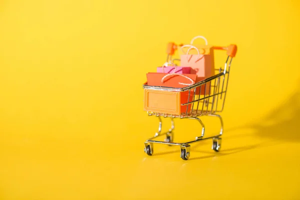 Petits sacs à provisions dans le panier de jouets sur jaune — Photo de stock