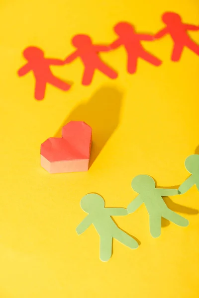 Origami coeur près de papier personnes sur jaune — Photo de stock