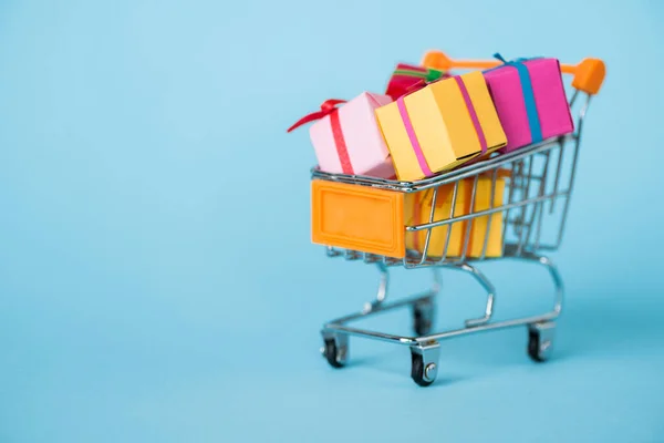 Pequeñas cajas de regalo en el carrito de compras de juguete en azul - foto de stock