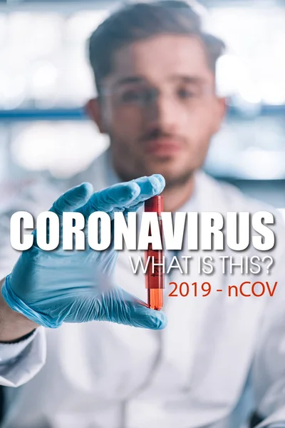 Selektiver Fokus des Epidemiologen im Reagenzglas mit roter Flüssigkeit und Coronavirus-Illustration — Stockfoto