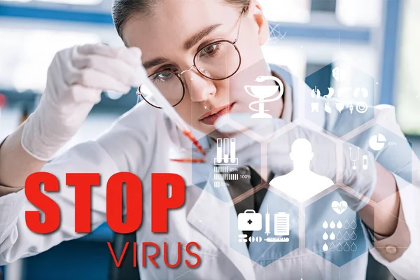 Selective focus of attractive epidemiologist holding pipette with red liquid in laboratory, stop virus illustration — Stock Photo