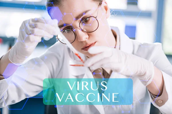 Селективная направленность привлекательного иммунолога, держащего пипетку с красной жидкостью в лаборатории, иллюстрация вирусной вакцины — стоковое фото